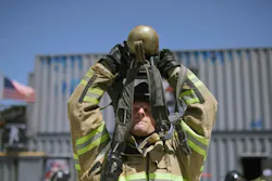 firefighter in turnout gear lifting SCBA canister during training