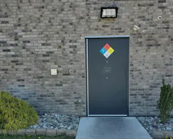 hazard-labeled door that leads to a room that has a carbon dioxide dewar container