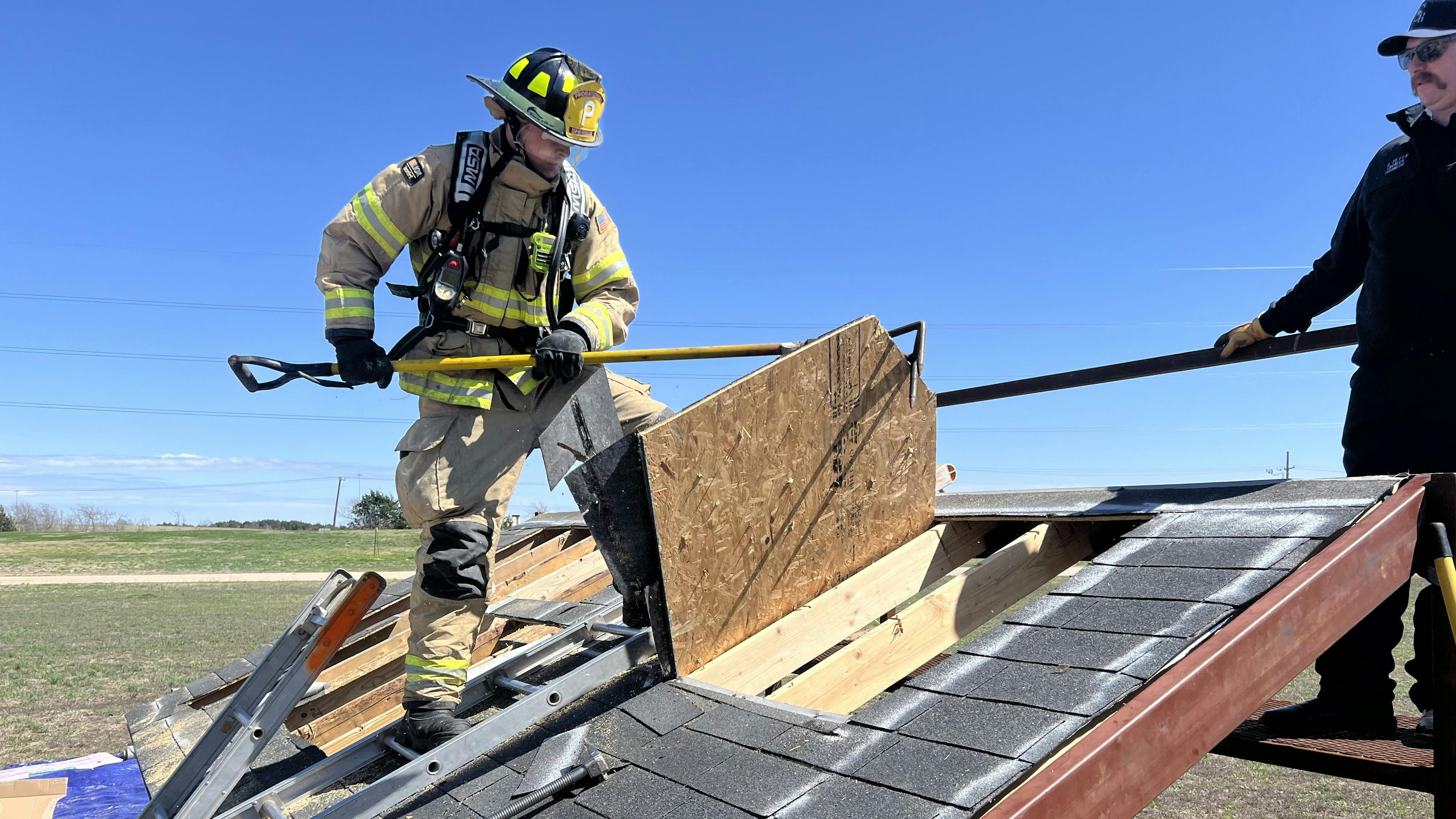 probationary firefighter being trained by officer on roof operations propr