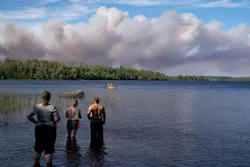 Observers wait along the shoreline of the Fall Lake entry point to the Boundary Waters Canoe Area Wilderness as paddlers approach to evacuate on Monday near Ely.