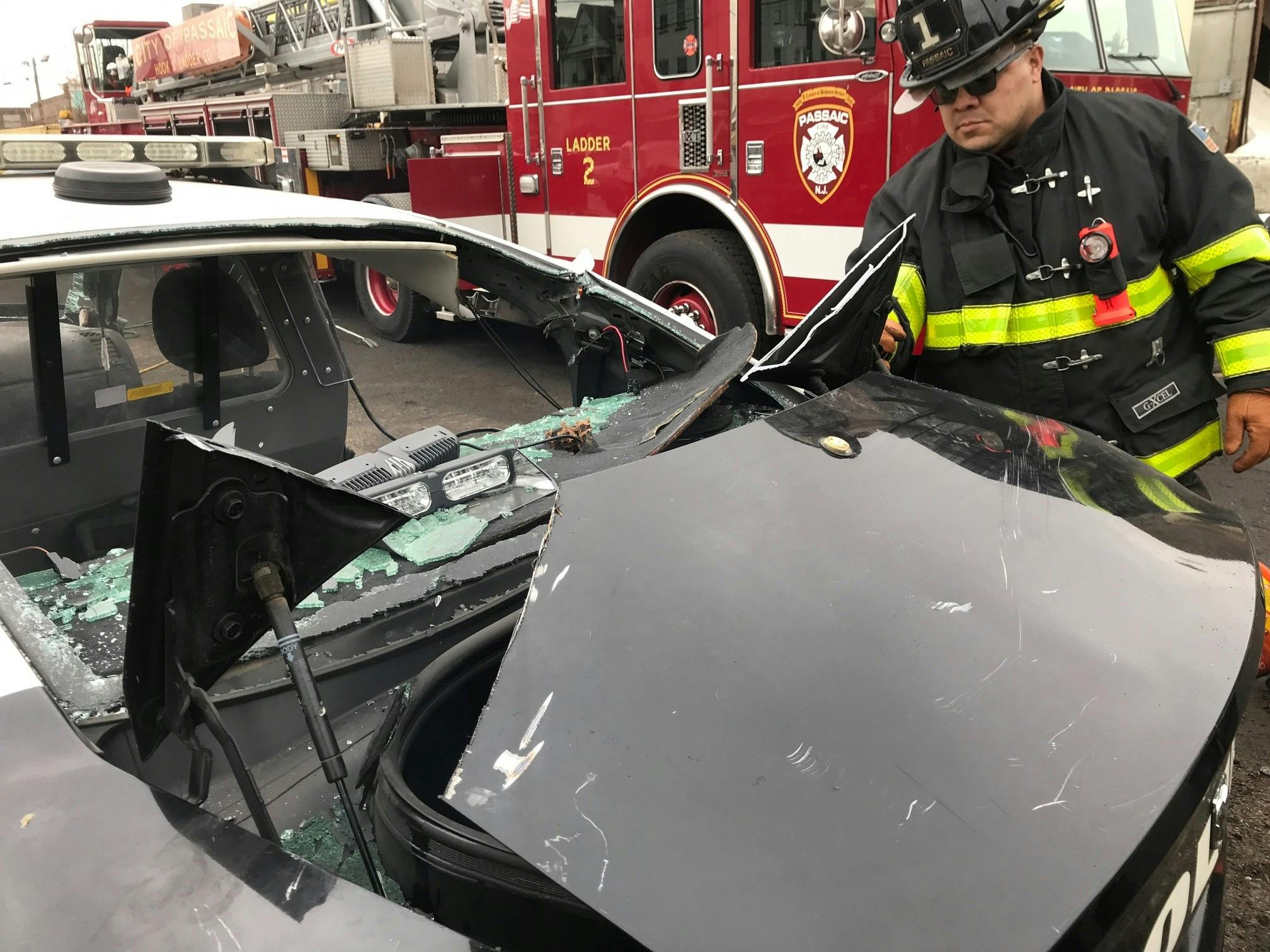 firefighter examining crashed police vehicle regarding occupant extrication