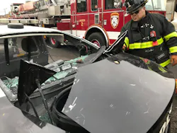 firefighter examining crashed police vehicle regarding occupant extrication