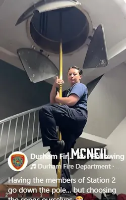 A Durham firefighter slides down a pole in a firehouse.