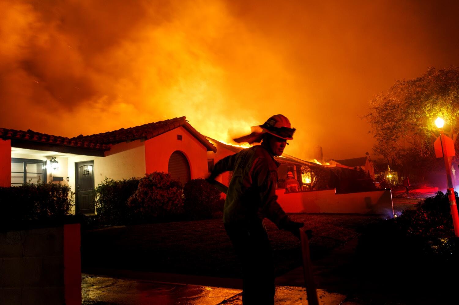 A firefighter races to grab a hose during the Eaton fire in 2025.