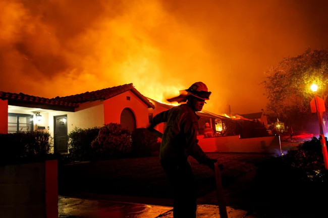 A firefighter races to grab a hose during the Eaton fire in 2025.