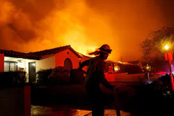 A firefighter races to grab a hose during the Eaton fire in 2025.