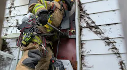 firefighter conducting forcible entry on a door at a house fire