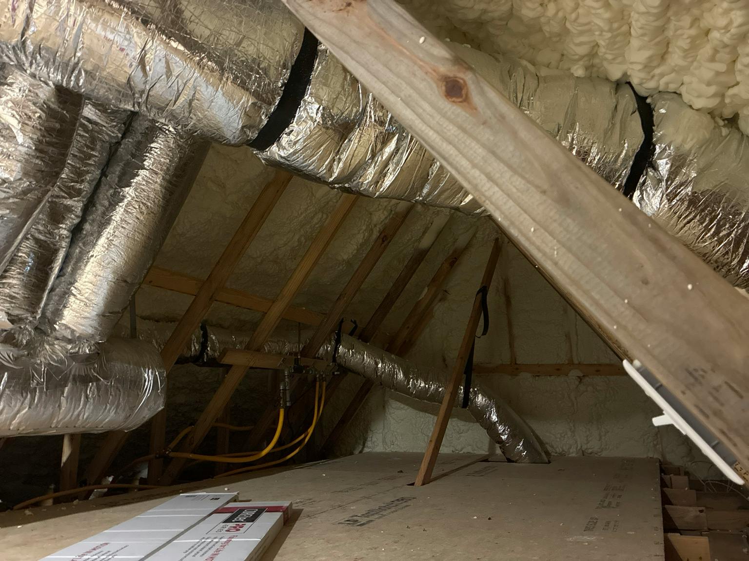 foam-insulated residential attic with ductwork that&rsquo;s located inside of the enclosure.