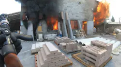 firefighter approaching building fire with hose in hand