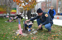 Baltimore Firefighter Kyle Higley and his son, Parker along with Lacey Marino, sister of Lt. Kelsey Sadler, place flowers at the Stricker Street Fire Memorial.